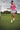 Woman in pink shirt and floral skirt jumping on a golf course